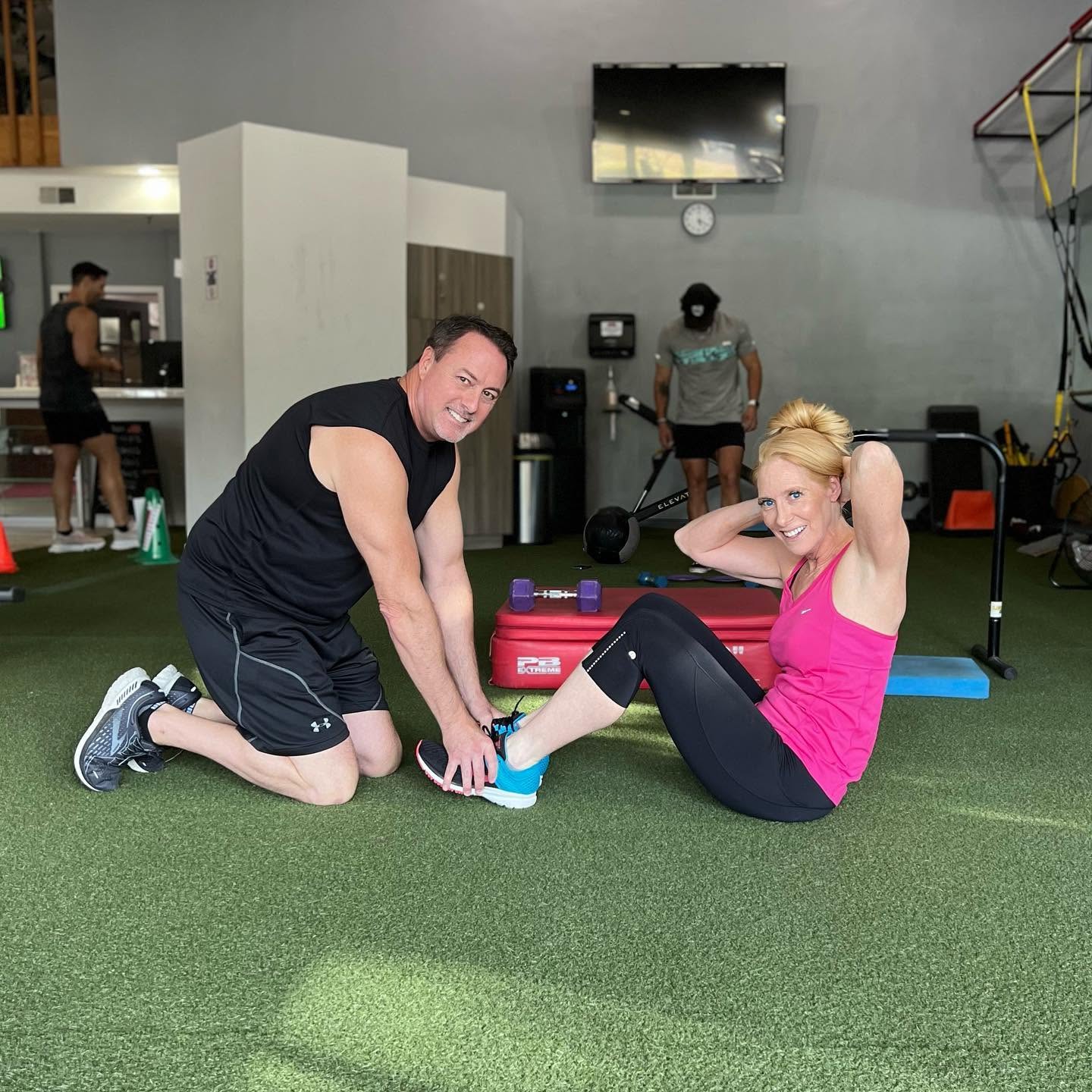 A LAVA 24 trainer coaching a member through core work on the turf